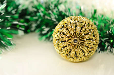 Christmas background with gold carved ball and green tinsel on white の写真素材