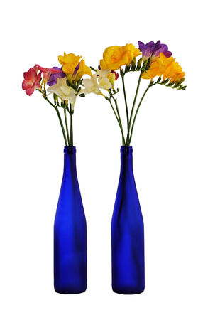 Two blue bottle with a bunch of colorful freesiaの写真素材