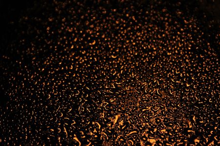 Abstract  background of water drops on window illuminated by street lamp