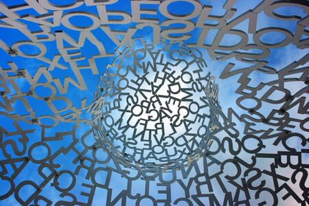 Random combination of letters organized in a certain circular shape against blue sky. View from belowの写真素材