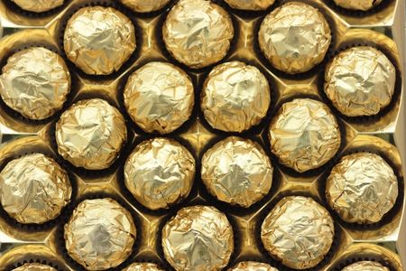 Pattern of round chocolate sweets in golden foil