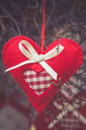 Handcrafted fabric heart hanging on a branch, fair goods, decoration for christmas tree or symbol of Valentineの写真素材