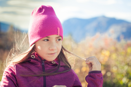 Smiling female teen kid with long hair and sportswear hiking in autumn morningの写真素材