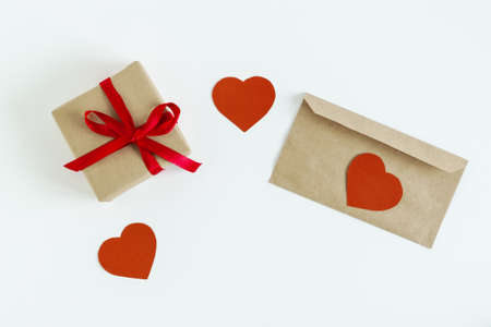 On a white background, a gift with a red ribbon, an envelope for a letter and hearts made of red...