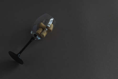Glass wine goblet with wine corks on a dark background. Horizontal photo with place for text. View...