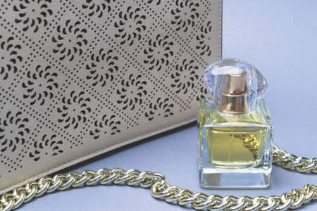 A set of women's perfume and an evening leather clutch bag on a gold metal chain.