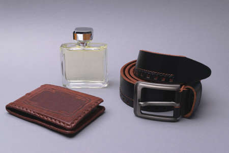A set of accessories for a stylish man. Expensive perfume, leather belt, business card holder on a...