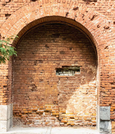 Arch in the wall made of old structural bricks. Textured background. Architectural elements. Horizontal photo.の写真素材