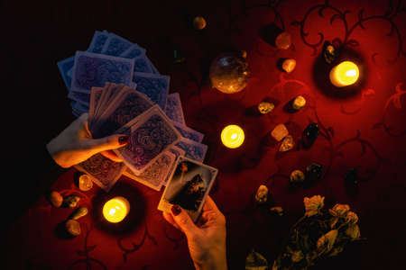Minsk, Belarus - November 2021: A fortune teller makes a Tarot layout and holds a Devil card in her hand. Magic and occultism.のeditorial素材