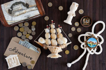 Vitebsk, Belarus - June 2021: On a dark wooden background, tourist magnets, coins, US banknotes, a knot, figurines, a chest, a ship made of shells.のeditorial素材