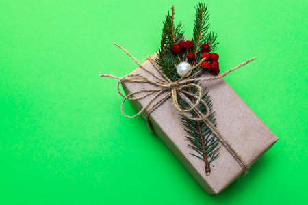 A Christmas gift. On a green background, a box with a gift with a spruce twig and rowan berries....