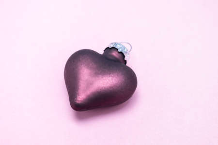 On a pink background, a purple Christmas tree toy in the shape of a heart. Christmas card....