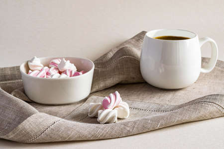 Hot fragrant coffee and sweet marshmallow in a white bowl on a linen serving napkin. Horizontal...