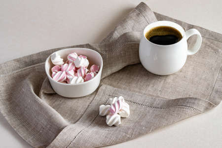 Hot fragrant coffee and sweet marshmallow in a white bowl on a linen serving napkin. Horizontal photo.の写真素材
