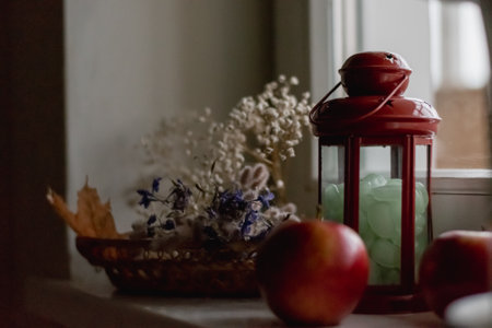 Still life in natural light from the window. Candlestick, apples and original flowers in a wicker...