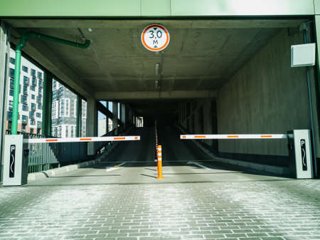Entrance to the covered multi-level parking for cars with a barrier and video surveillance. horizontal photo.の写真素材