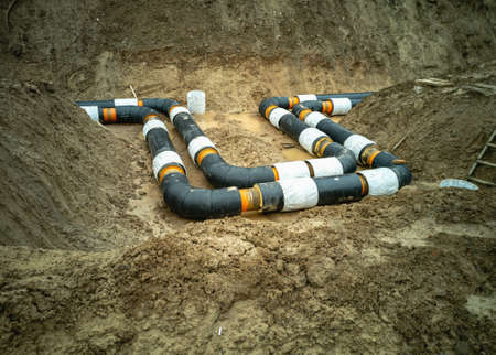 Water pipes for supplying communications lie in a trench dug in the ground.の写真素材