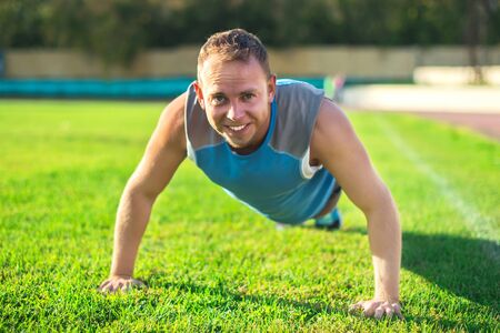 sport man stretching at the park, doing push-ups on  grass  a sunny day. Fitness concepts.