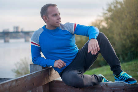 Attractive man sitting on beach in the evening  after sportの写真素材