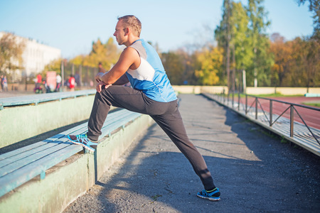 Athletic man trains, stretched on bench  stadium. concept of health and strengthの写真素材