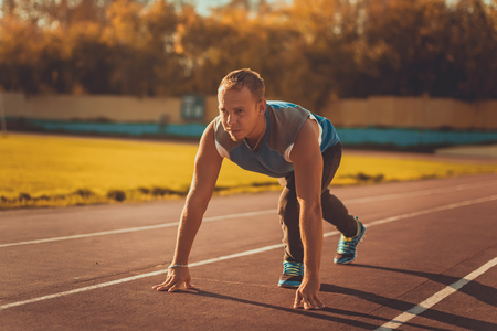 Athletic man standing in a posture ready to run on a treadmillの写真素材