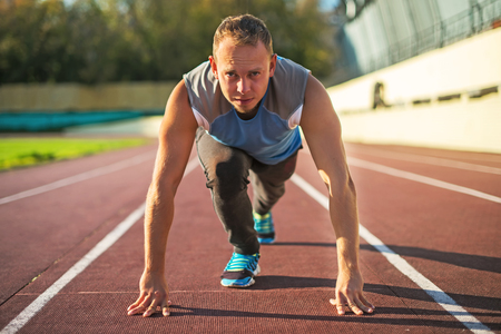 Athletic man standing in a posture ready to run on a treadmillの写真素材