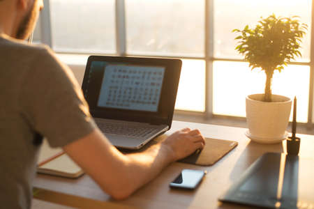 young man working with notebook, view from the back , business  man in the office, sunset or sunrise workplace.の写真素材