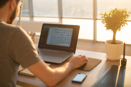 young man working with notebook, view from the back , business  man in the office, sunset or sunrise workplace.の写真素材