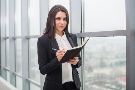 Young beautiful business woman with a notebook is the window in the office.の写真素材