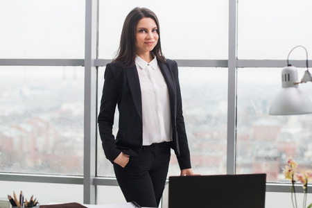 Young beautiful business woman standing at the window in the office.の写真素材