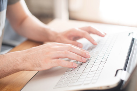 Hands typing on a notebook closeup. Workplace.