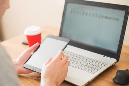 Workplace. Hands holding a tablet and a notebook closeup.