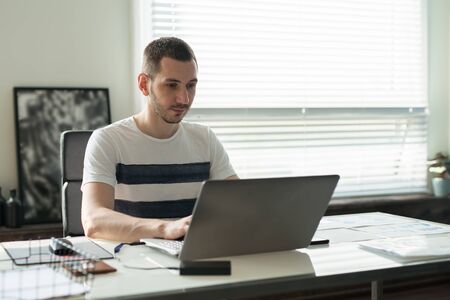 Young business man working on a laptop at his desk in the office.