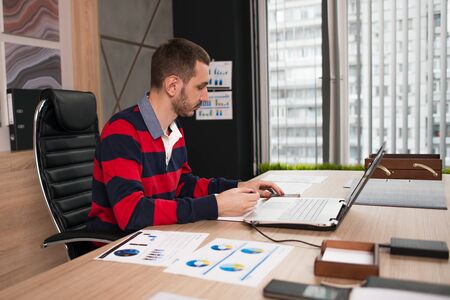 Young business man working on a laptop at his desk in the office.