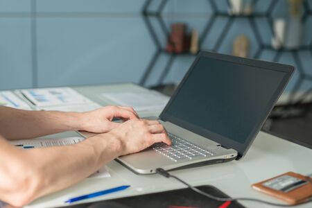 young man working with laptop, view of hands on notebook , business person at workplace.