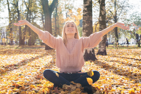 Attractive young woman smiling and throwing leaves up in the air.の写真素材
