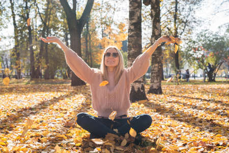 Attractive young woman smiling and throwing leaves up in the air.の写真素材