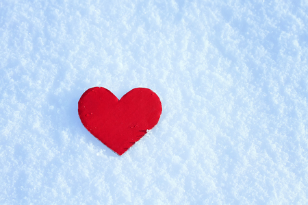 Red paper heart lying on the white snowの写真素材