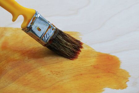 brush  covering the wooden surface with a solution of stain