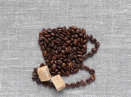 Cup of roasted coffee beans with two slices of cane sugarの写真素材