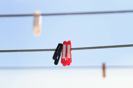 multi-colored plastic clothespins hanging on the clothesline on a blue sky backgroundの写真素材
