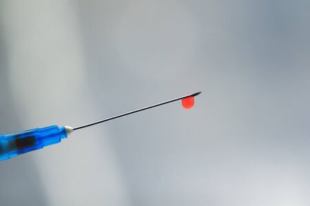 needle of syringe with blood drop at the tipの写真素材