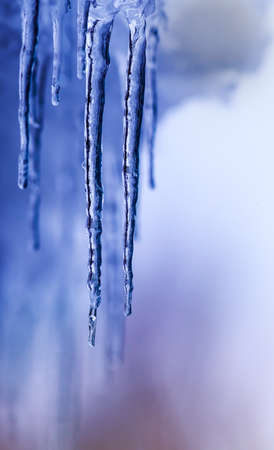 shiny, transparent icicles hanging from the roof on a Sunny dayの写真素材