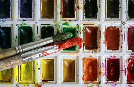 background of the brush covered in paint lying on a set of bright watercolorの写真素材