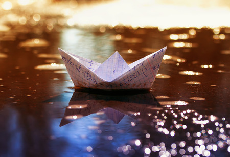 children's school the little paper boat of cellular notebooks swims in the early spring sun puddleの写真素材