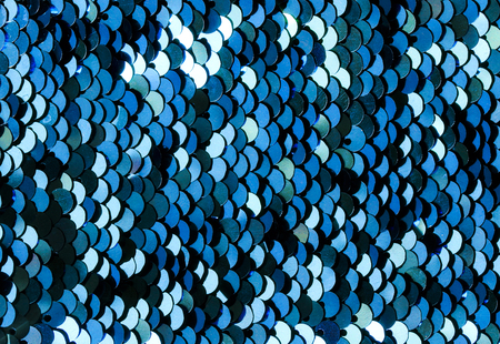 shiny beautiful background texture set of round sequins blue sewn on fabric and imitating fish...