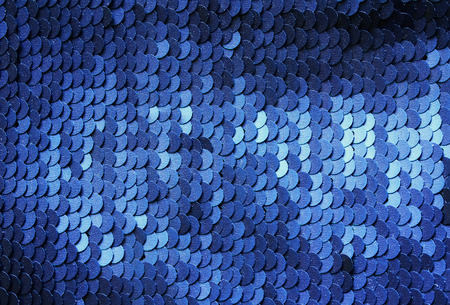 beautiful shiny texture background lots of colorful sequins in blue colors sewn on fabric as scales