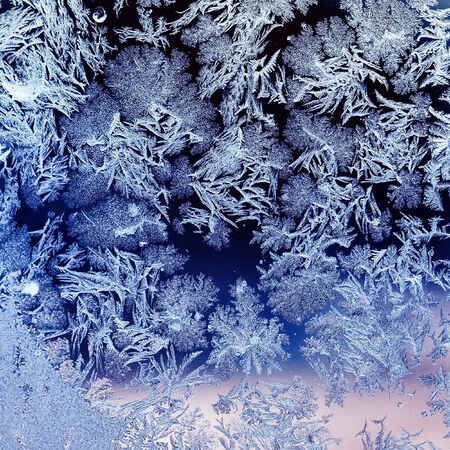 square beautiful background with texture of frozen ornate frost patterns on glass on a cold winter...