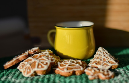 Christmas gingerbread cookies on a green background and a yellow mug