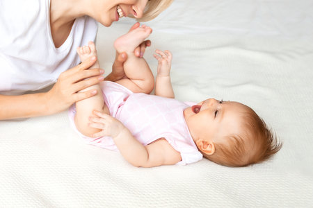young mom playing with baby on the bed, close-up.